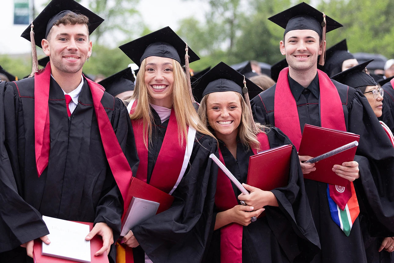 Four IU Northwest graduates pose in their caps and gowns.