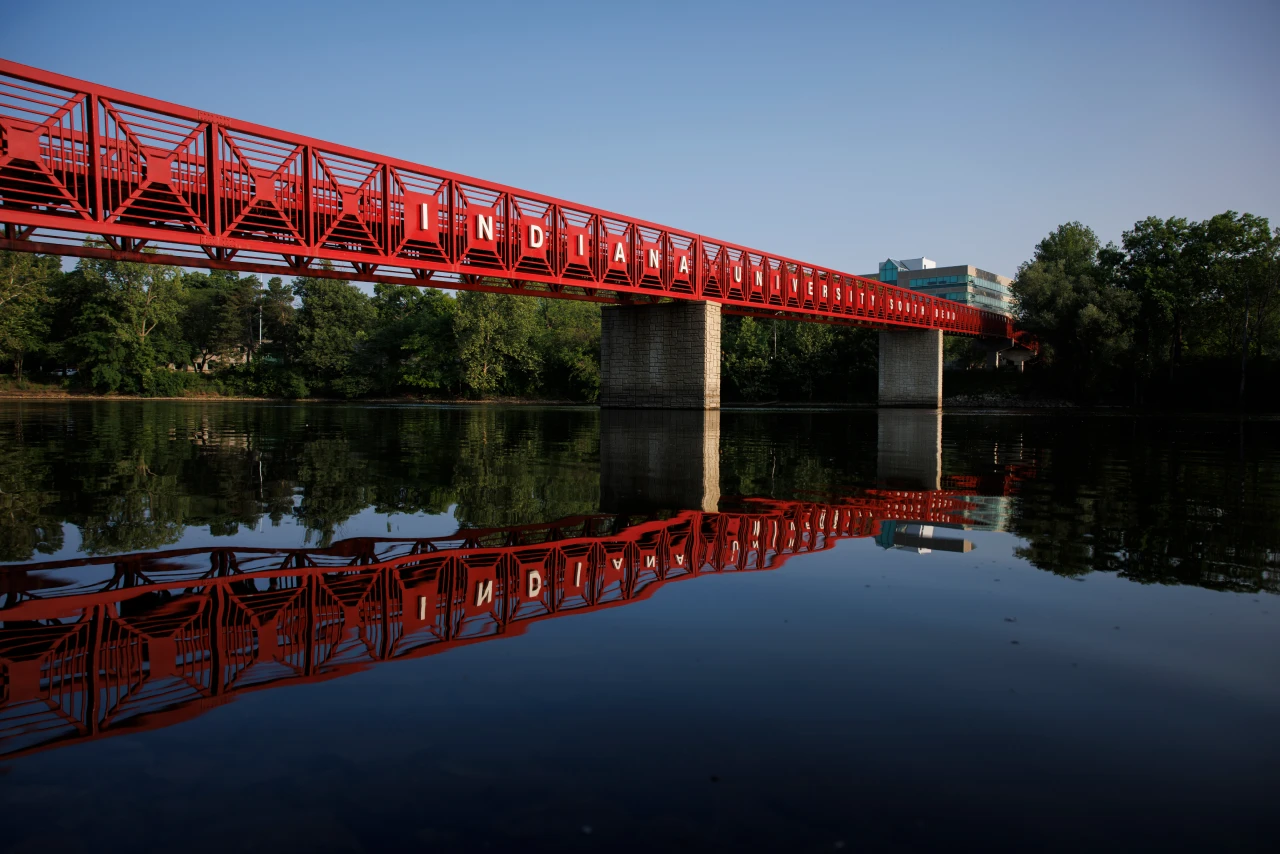 Bridge with text Indiana University South Bend stretching over a calm river